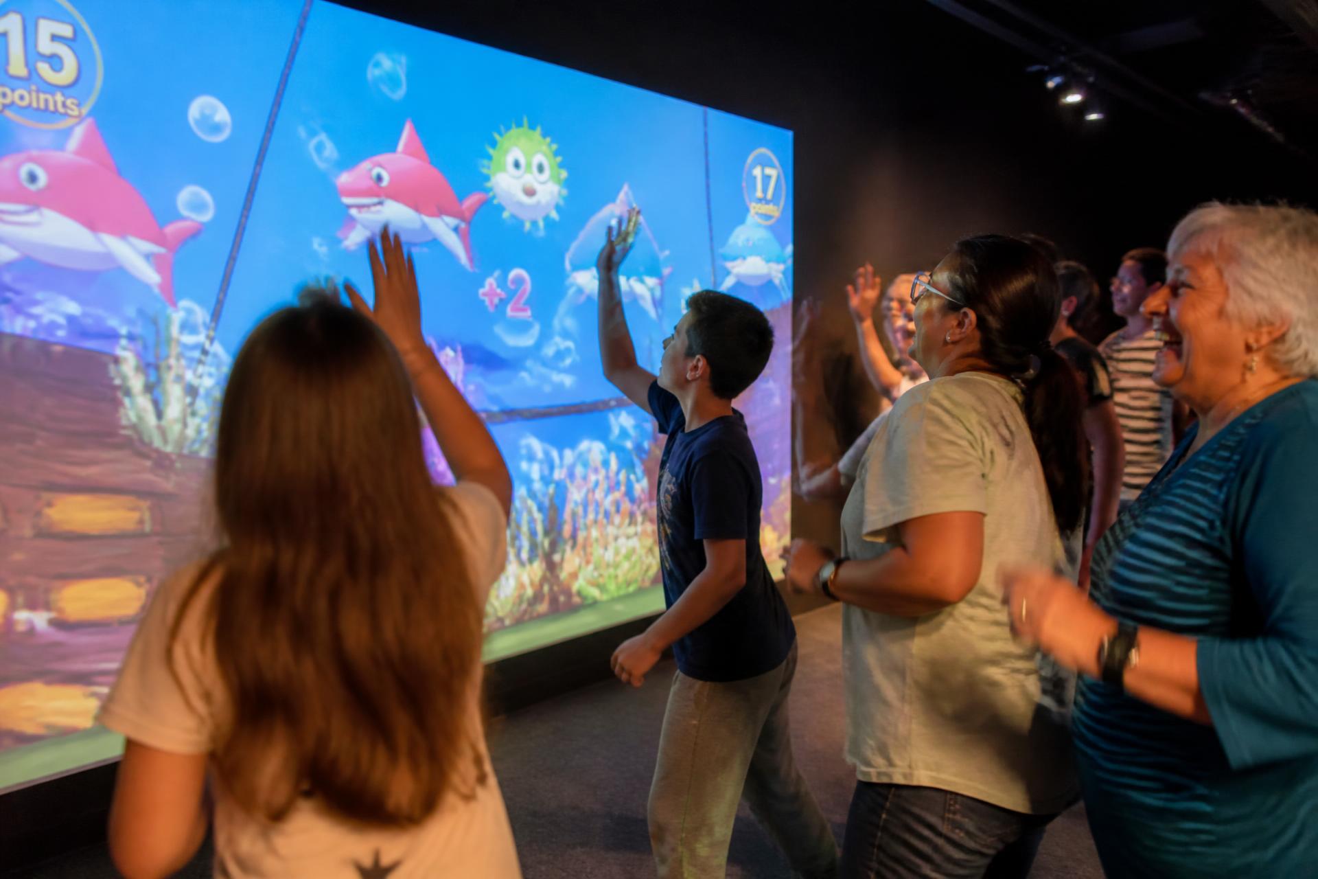 Les 50 jeux interactifs Play'In Village : participants de plusieurs générations en mouvement devant un grand jeu projeté