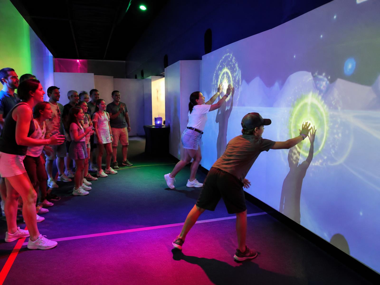 Participants qui se relaient devant le mur de jeu interactif